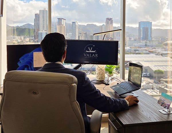 Omar Vaquerano standing in his office, looking thoughtfully out a window with natural light illuminating the room.